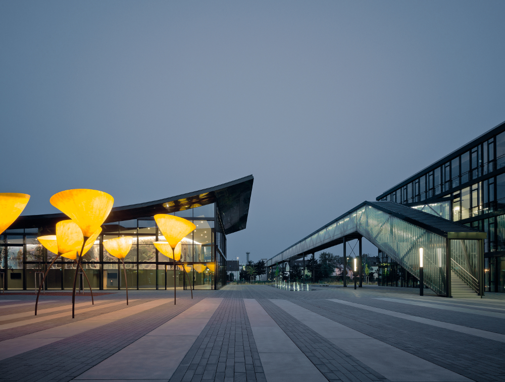 Kärcher Winnenden Nachtansicht Vorplatz mit Viabizzuno Außenleuchte maxxi poppy in Form einer Mohnblume