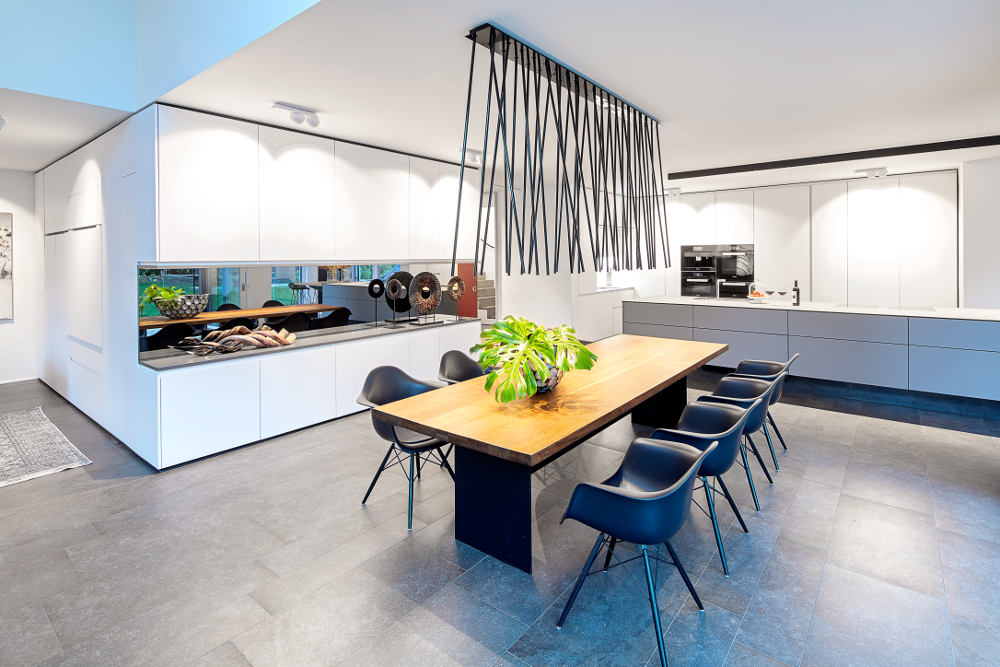 Esstischbeleuchtung mit der Leuchte peled von Viabizzuno im Vordergrund und Küchen- und Wandbeleuchtung mit inVision Leuchte von O/M und Marbul von Modular im Hintergrund